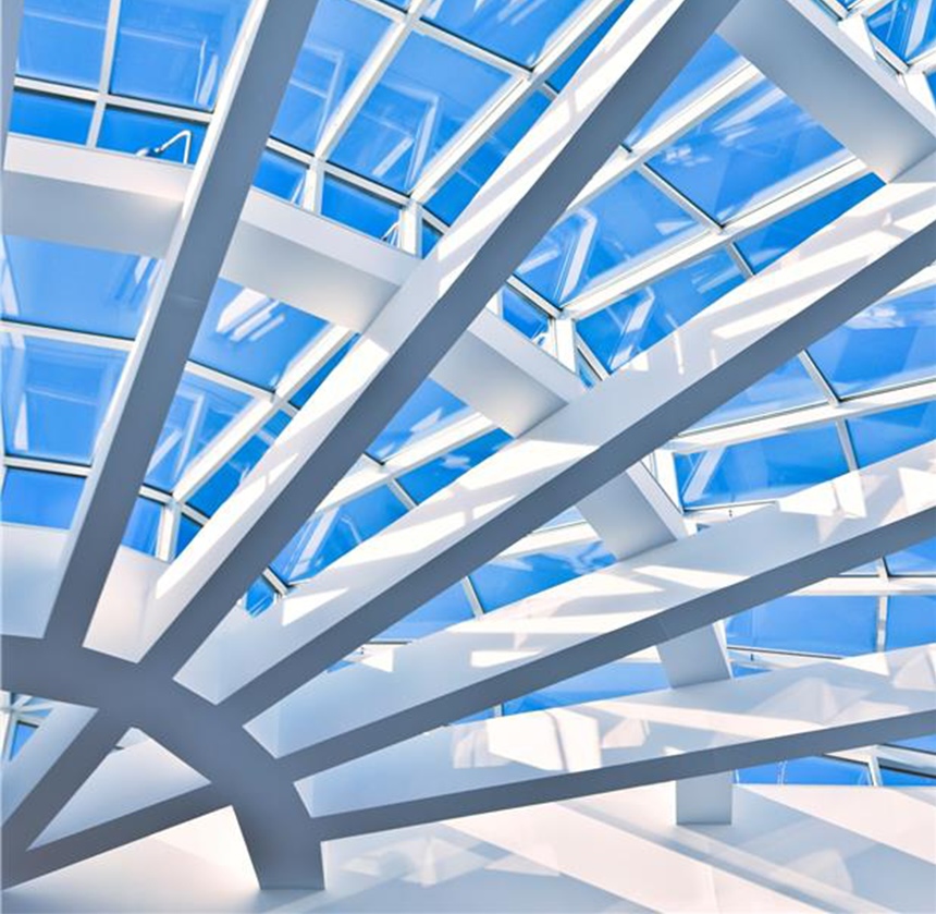 Techo arquitectónico moderno con vigas blancas entrecruzadas y grandes paneles de vidrio, con un cielo azul brillante al fondo.
